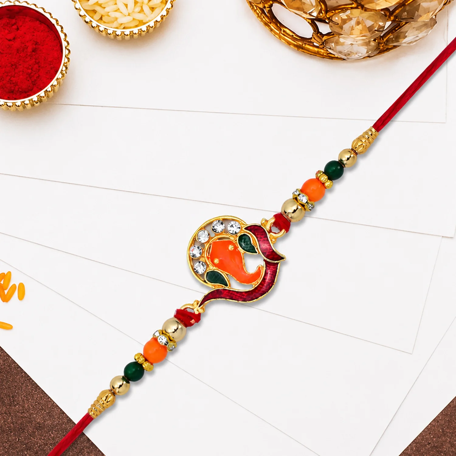 Golden Ganesha Rakhi – Red & Green Beads with Stone Detailing - Image 2